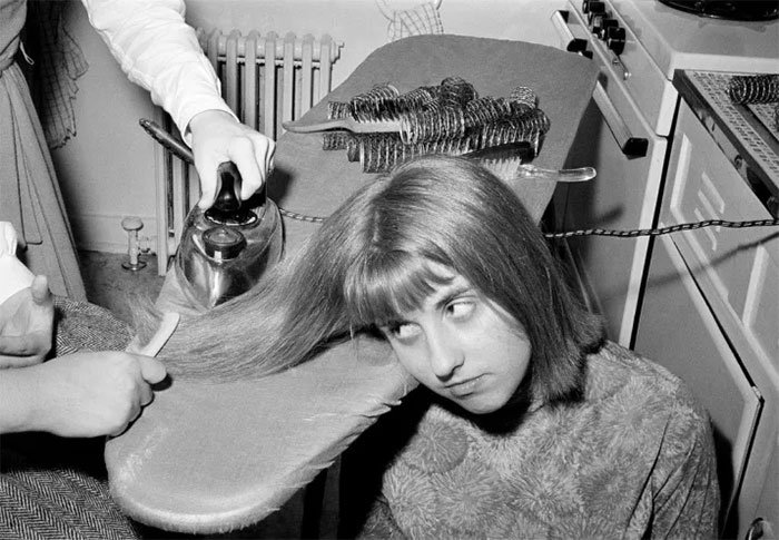 mulher passando ferro no cabelo - Coisas estranhas do passado a que as mulheres se sujeitaram em nome da beleza (Não se assuste!)